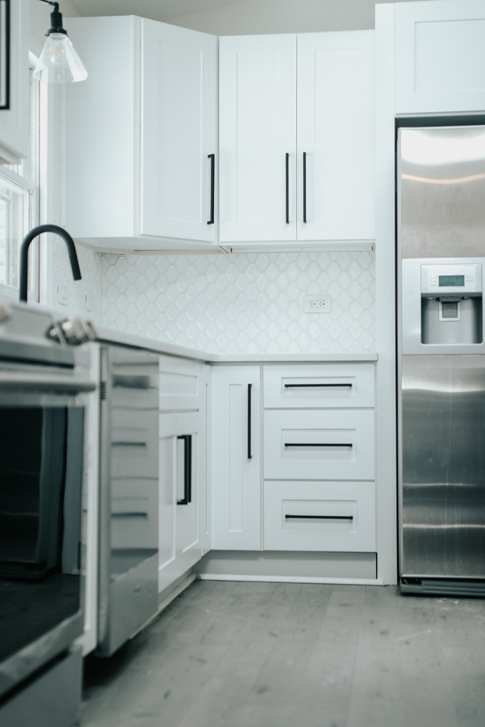 A white kitchen with light hardwood floors and stainless steel appliances. A white kitchen with light hardwood floors and stainless steel appliances.