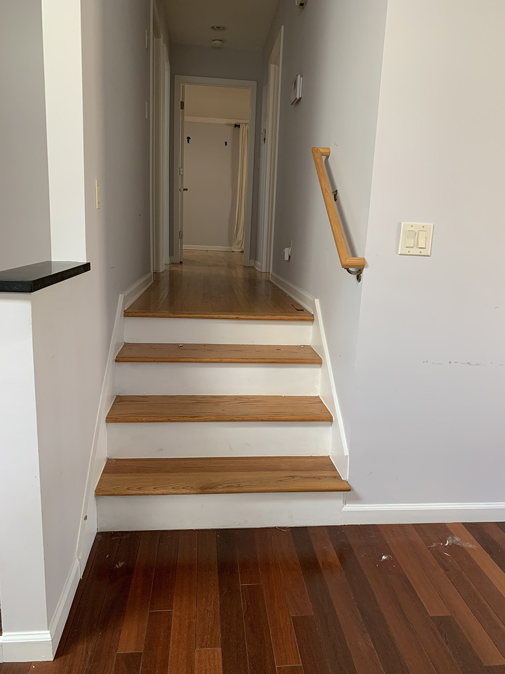 Two colors of hardwood flooring meet at the bottom of a stairway. Two colors of hardwood flooring meet at the bottom of a stairway.