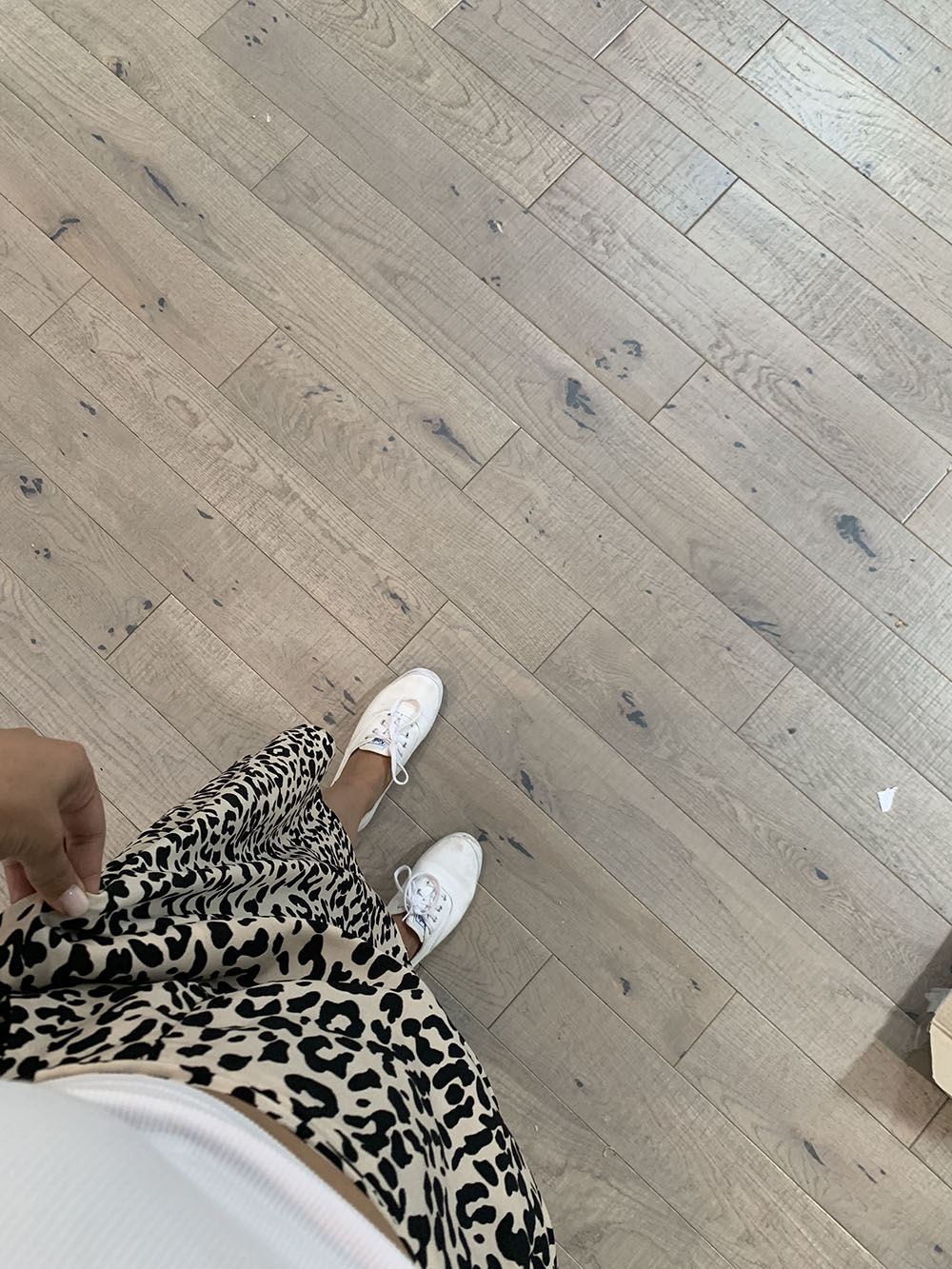 A person in white shoes standing on new hardwood floors. A person in white shoes standing on new hardwood floors.