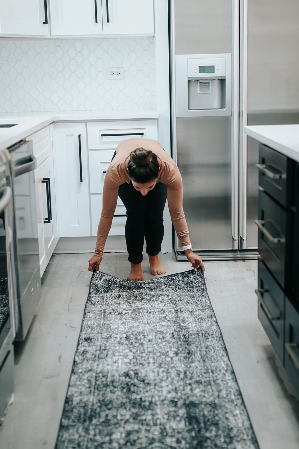 A woman adjust a rug on kitchen floors. A woman adjust a rug on kitchen floors.