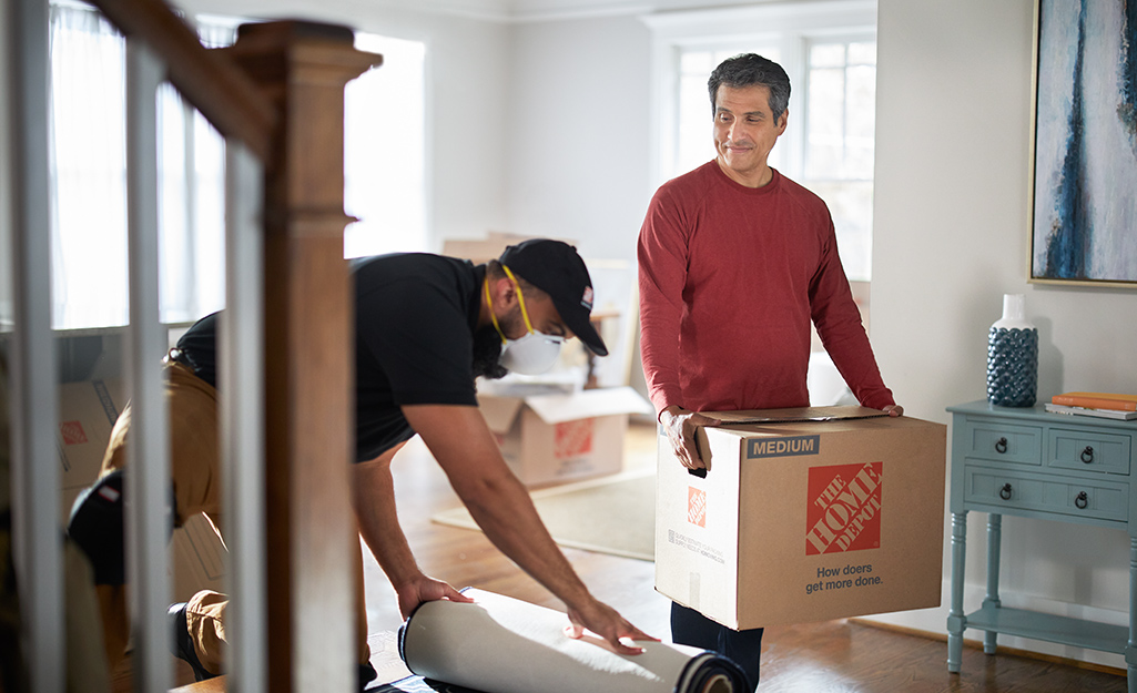 Homeowner walking through living room with Home Depot moving box.