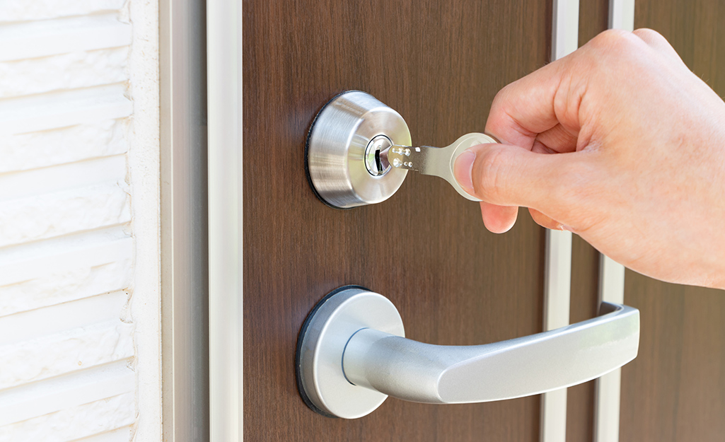 A hand inserting a key into a front door lock.