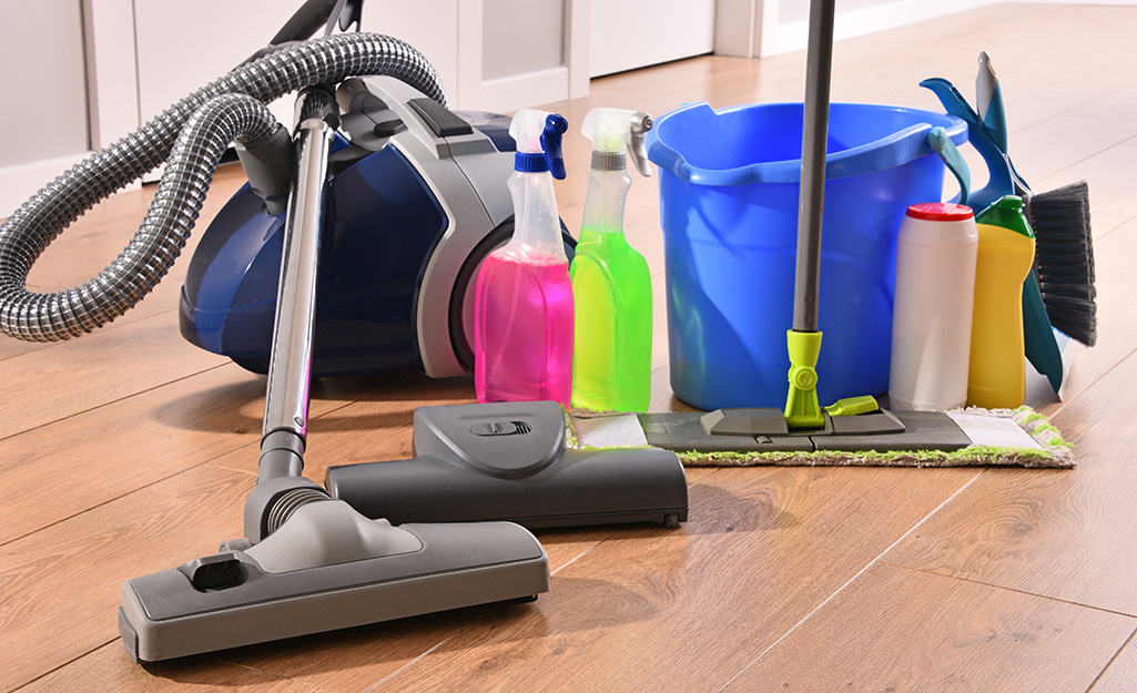 An assortment of cleaning supplies on a wood floor.
