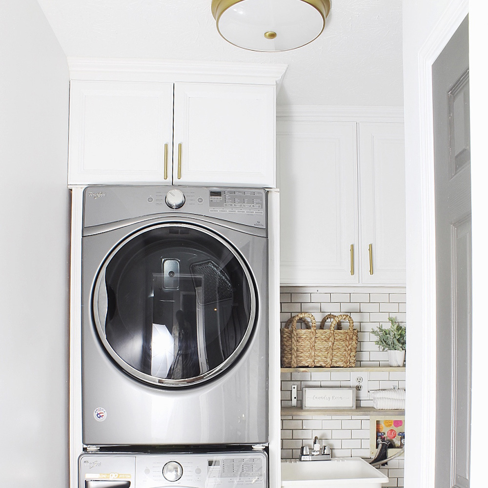 A white laundry room with front load stackable laundry appliances.