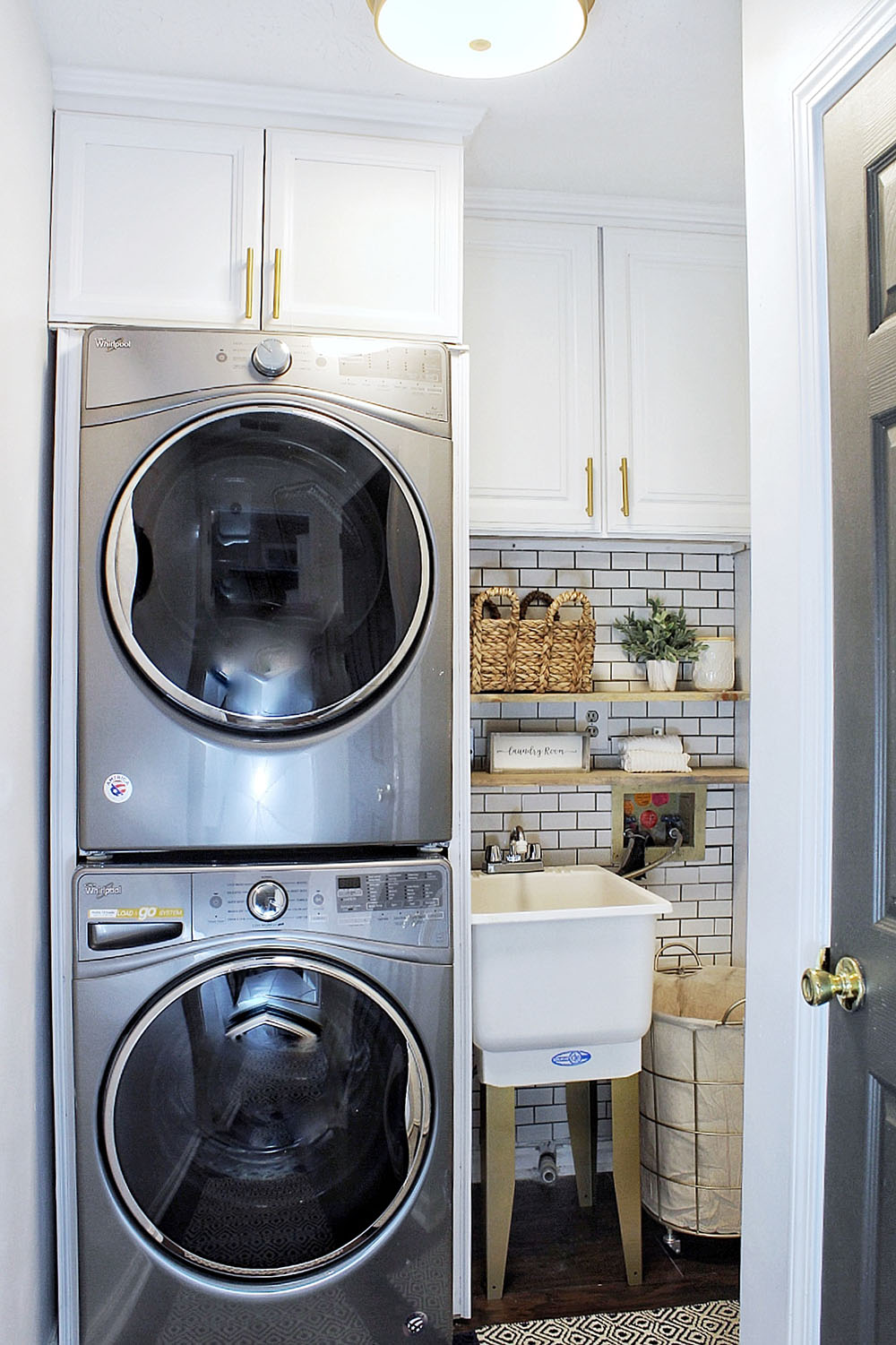 A completed small laundry room update with new appliances, cabinets, and shelving.