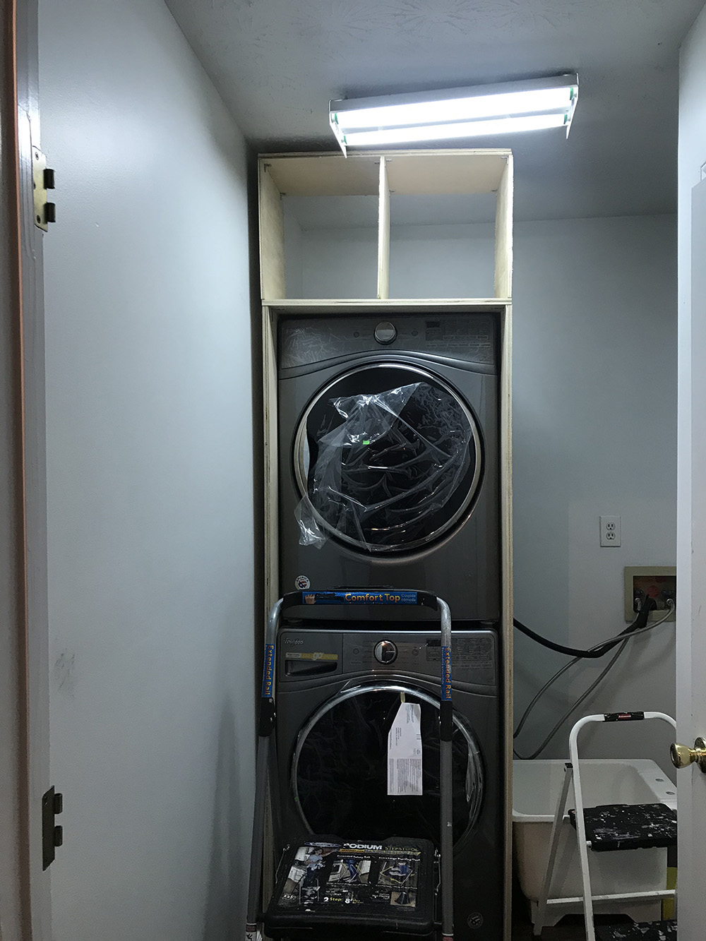 A stacked washer and dryer is framed out with cabinetry.