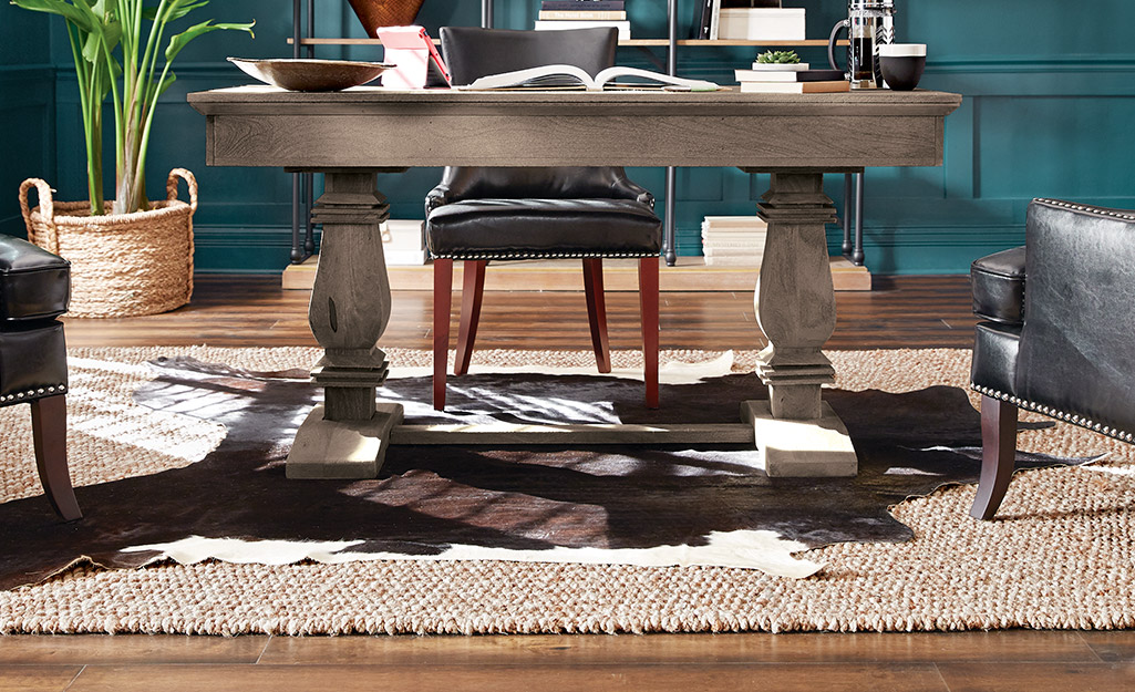 Layered rugs under a pedestal desk.