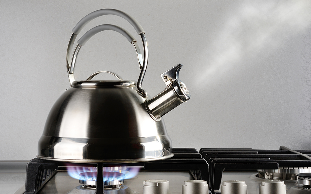 Tea pot boiling on a stove. 