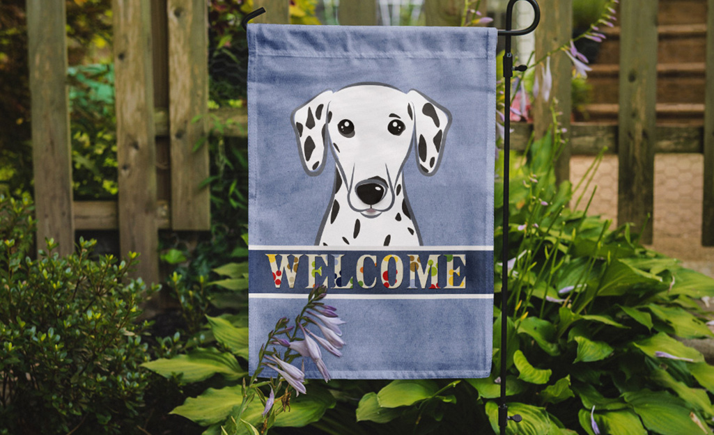 A garden flag showing the word "welcome" hanging outside a home.