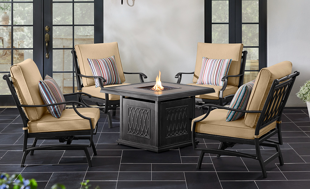 A contemporary fire pit with outdoor chairs on a patio.