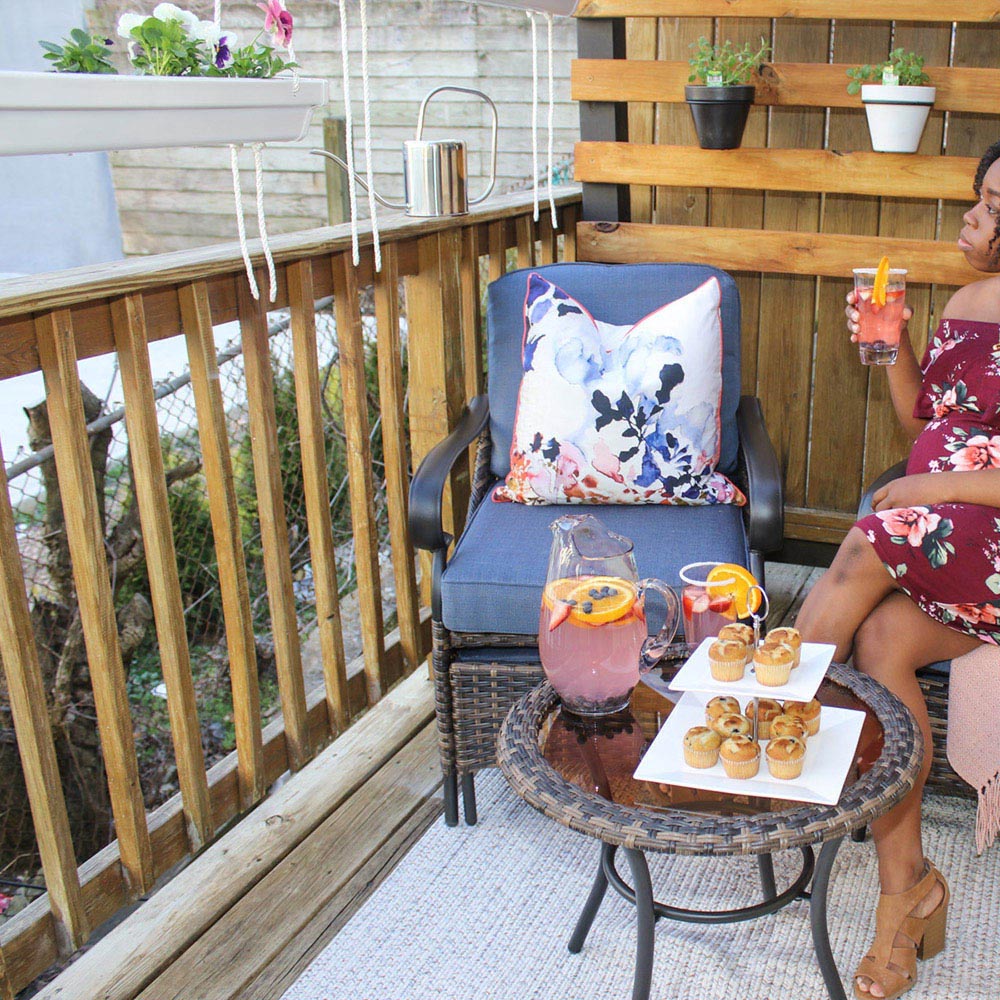 A woman sitting on a small balcony with wall planters.