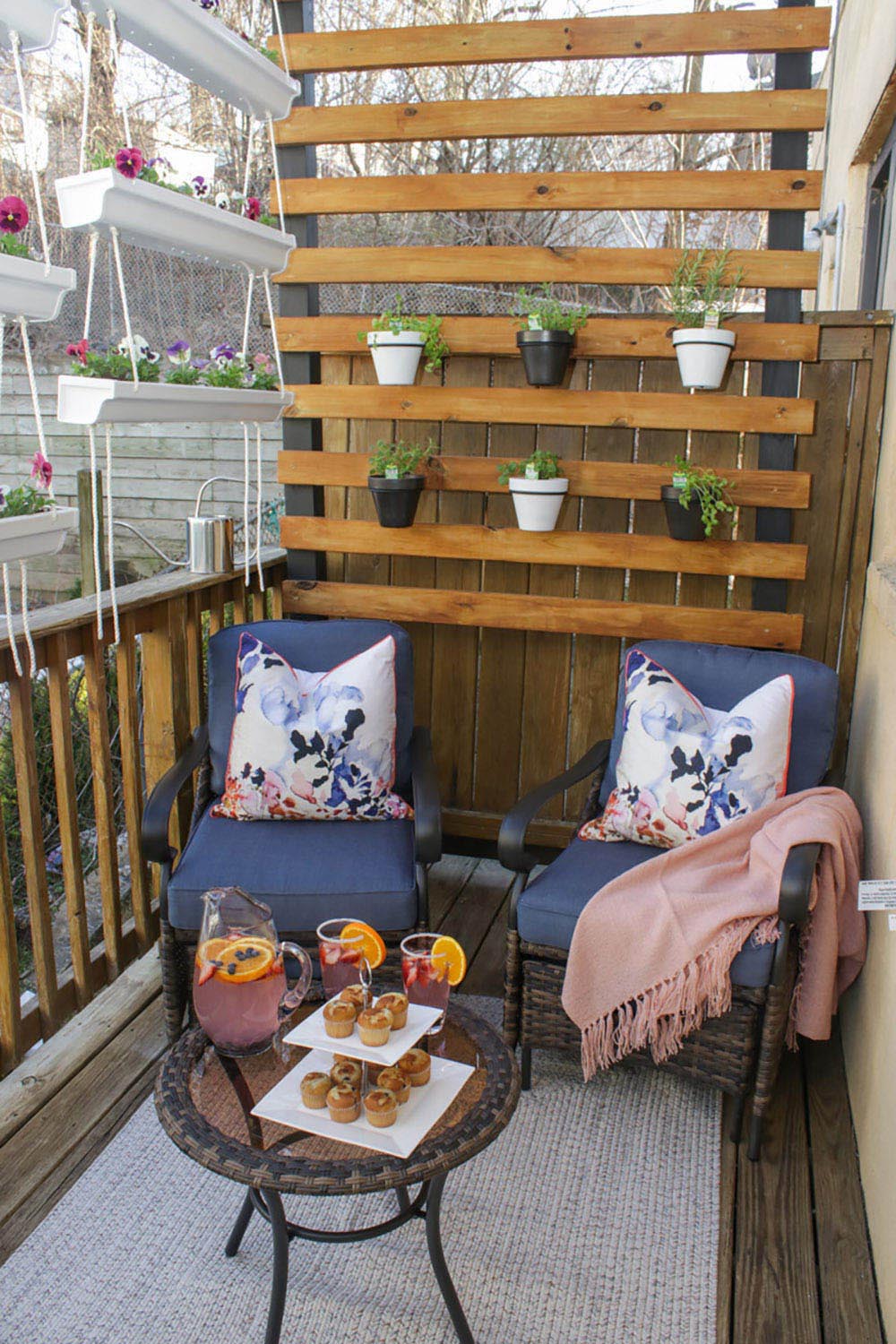 A wooden wall planter behind two patio chairs.
