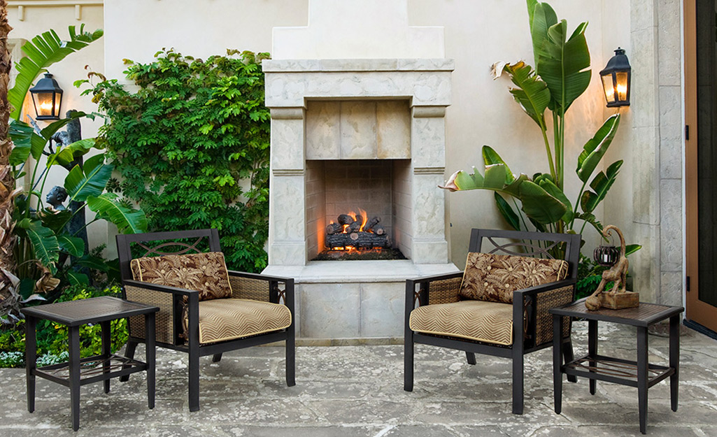 An outdoor fireplace made of light-colored stone on a patio.