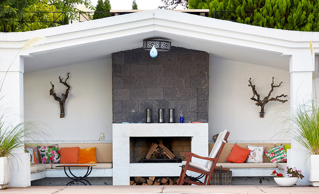 An elegant patio with a polished stone outdoor fireplace and built-in benches..