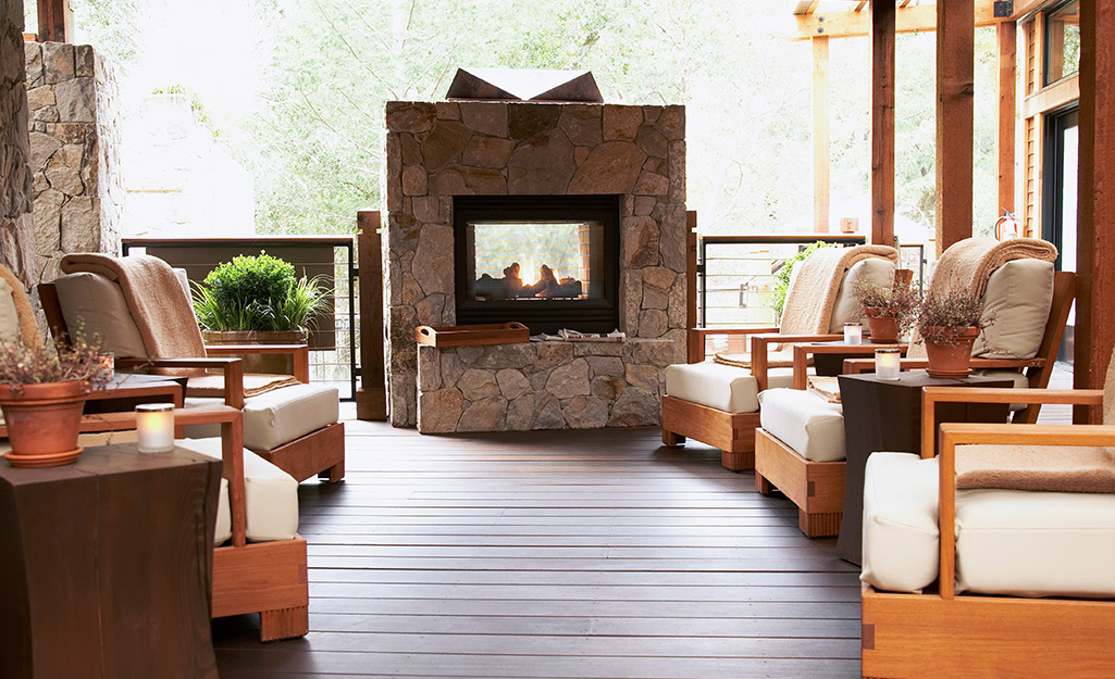 A hygge hearth surrounded by cozy wood patio furniture.
