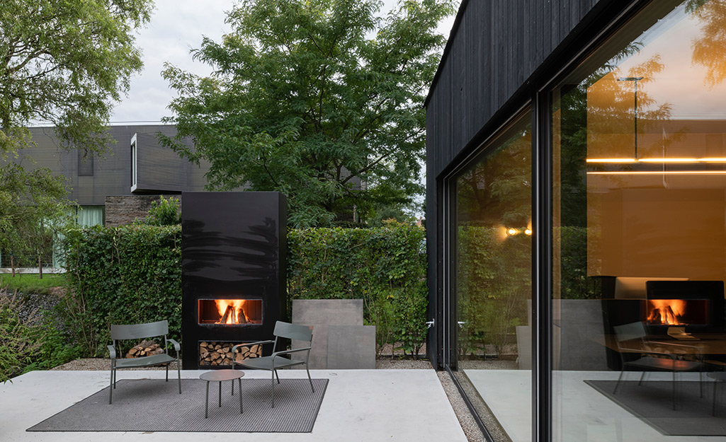 A black outdoor fireplace on a patio featuring modern seating..