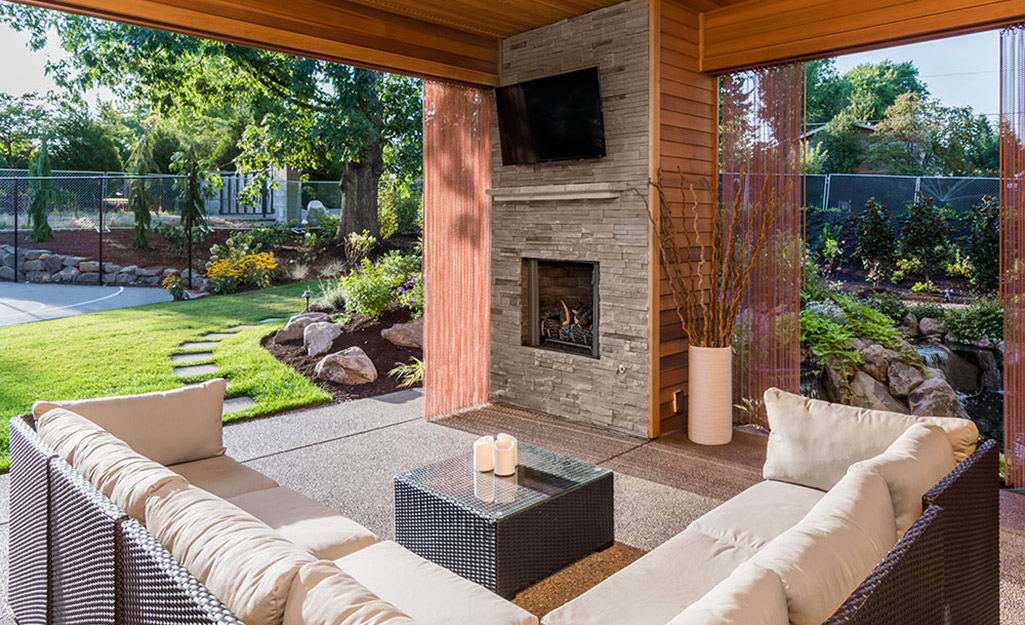 A modern outdoor fireplace has a gas fire and  sectional seating.