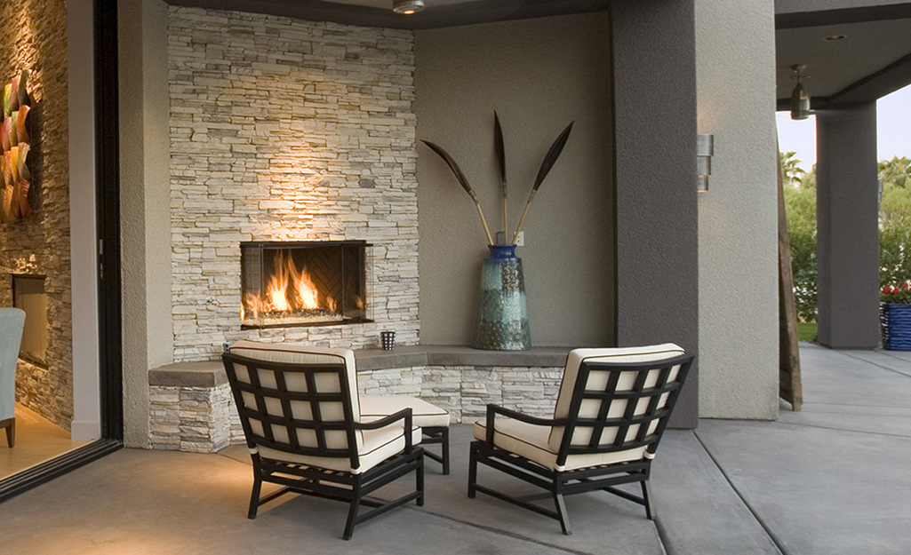 An outdoor fireplace has a modern feel on a covered patio.