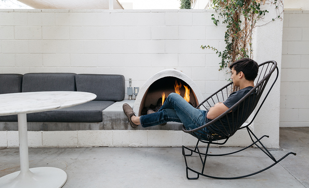 A man relaxing by a modern outdoor fireplace.