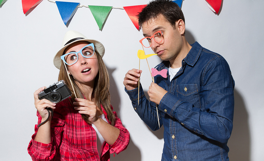 A couple uses props from a photo booth for pictures.