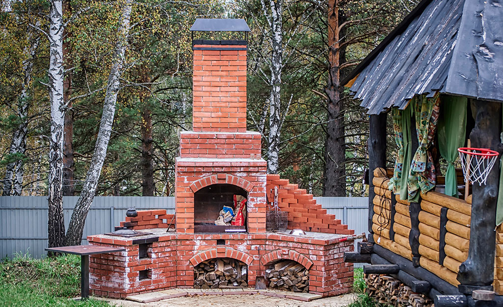 An outdoor brick kitchen with a fireplace.
