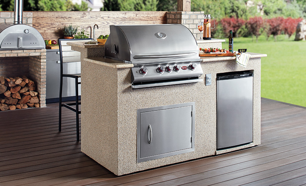 An outdoor kitchen with a built-in grill and refrigerator.