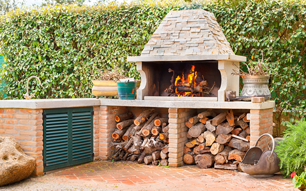 A wood and stone rustic outdoor kitchen with firewood oven.