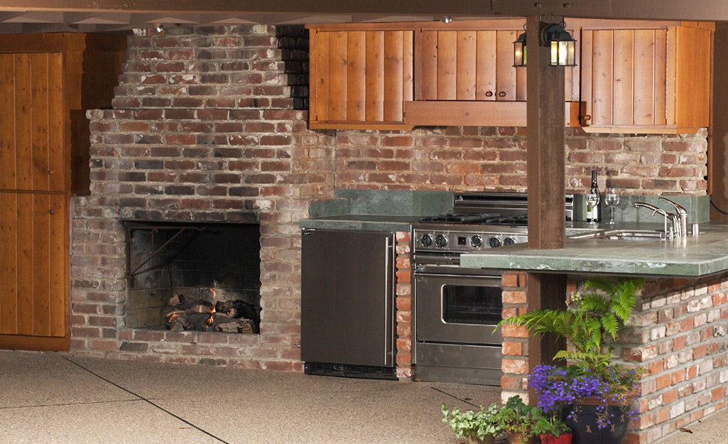 An outdoor kitchen with a brick fireplace.