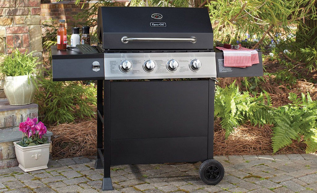 A portable grill with wheels on a patio.
