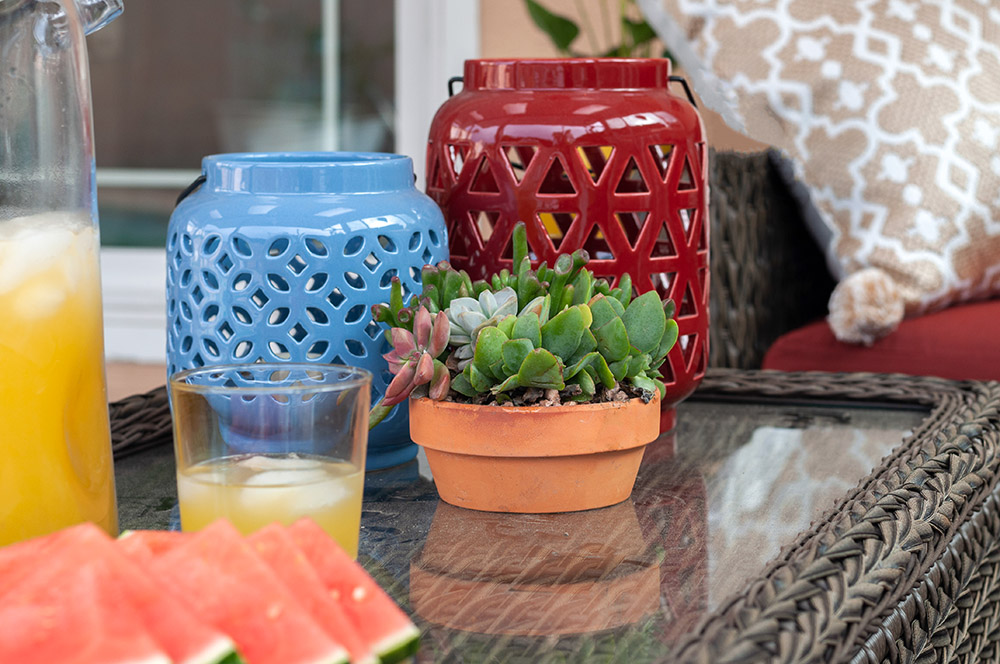 A table decorated with a succulent arrangement and red and blue ceramic lanterns.