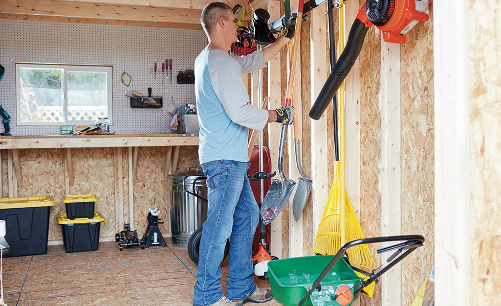 Someone gathering lawn care tools from a shed.