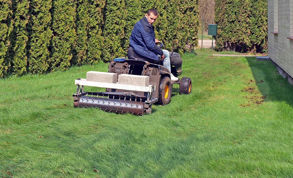 Someone pulling an aerator across a lawn.