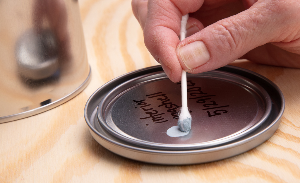 Someone applying a dab of paint to the lid.