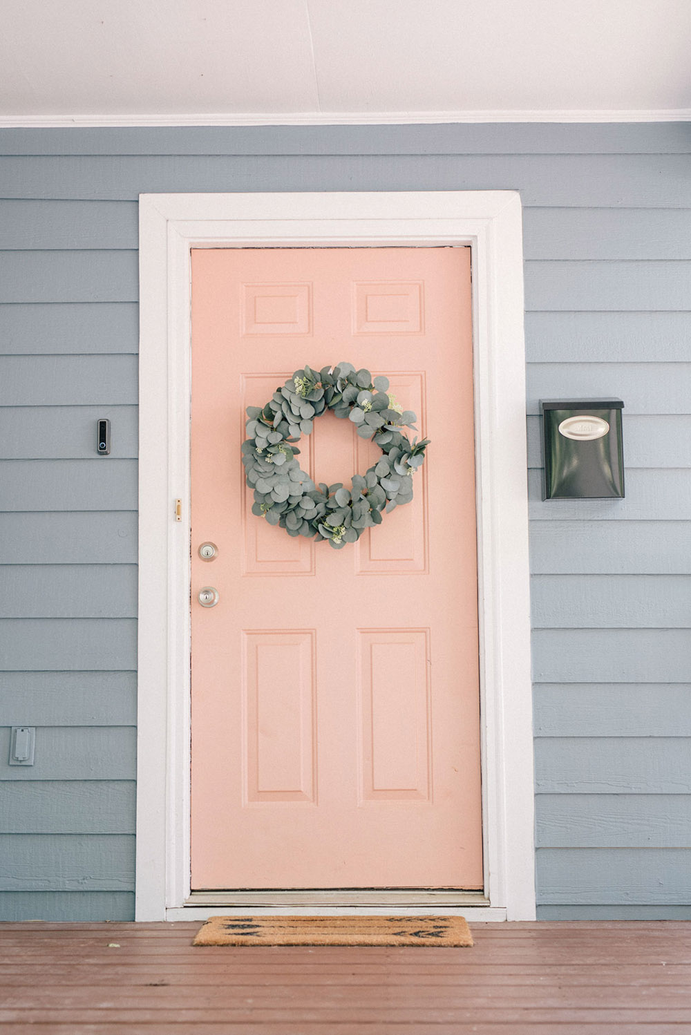 A pink door with white trim on a blue painted home.