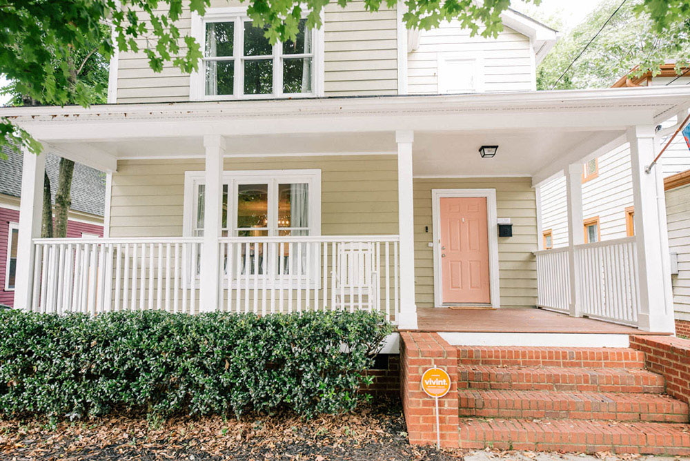 The exterior of a beige home with a pink door.