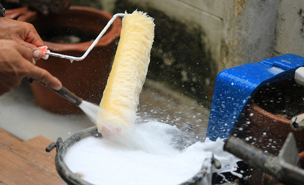 A person washing a paint roller.