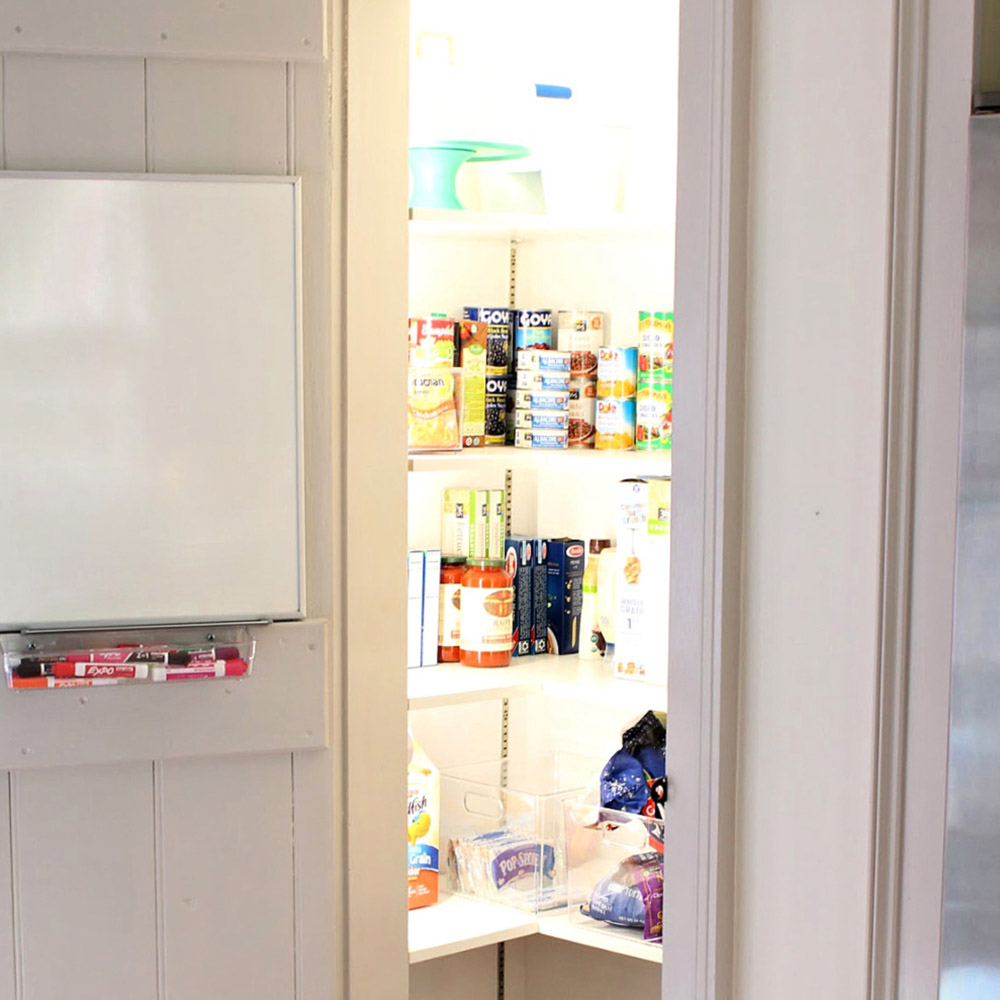 The inside of a stocked pantry with white shelving and lights.