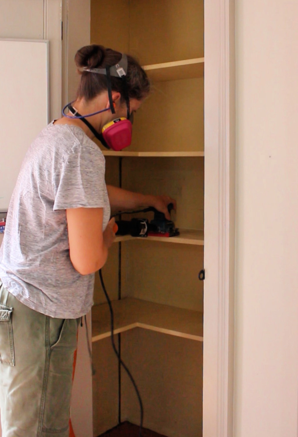 A woman sanding shelves in a pantry.