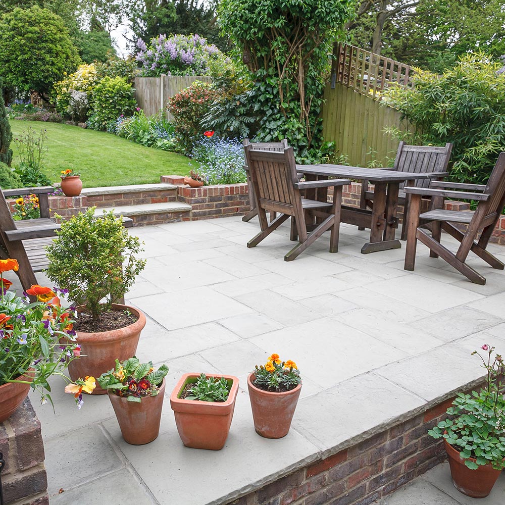 A patio with potted plants, a table and chairs.