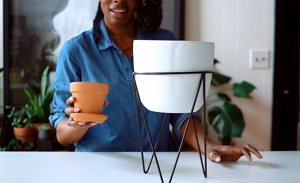 Woman placing a terra cotta planter on a table.