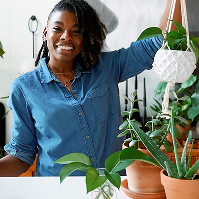 Woman holding up a hanging basket.