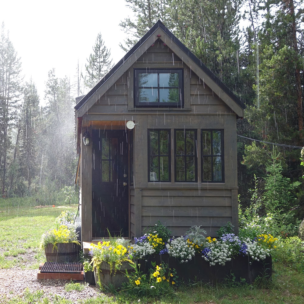 A tiny home with a flower garden out front.