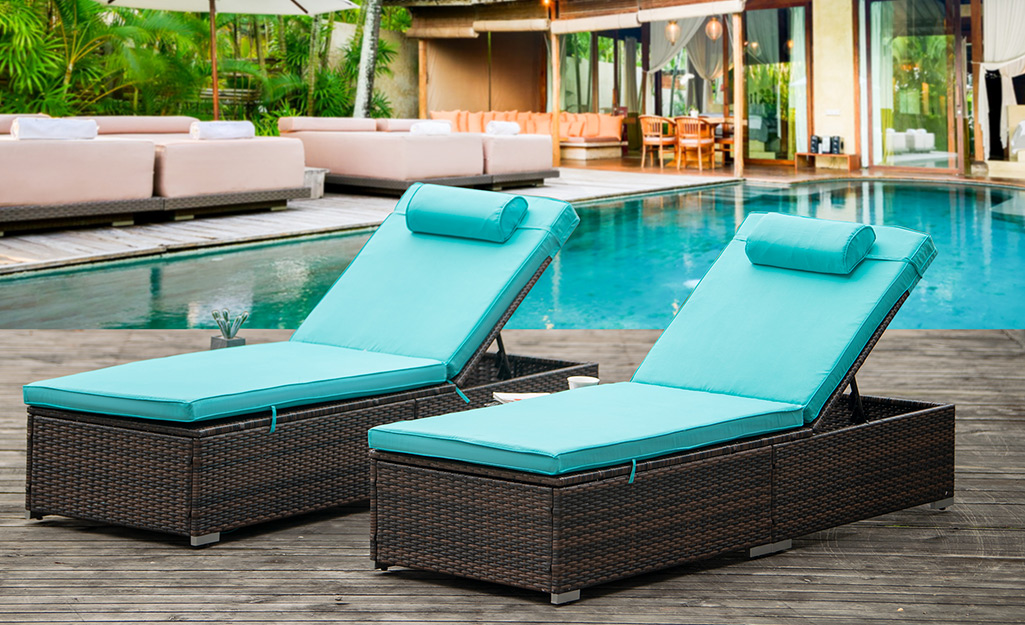 Luxurious dark brown wicker poolside loungers with turquoise cushions