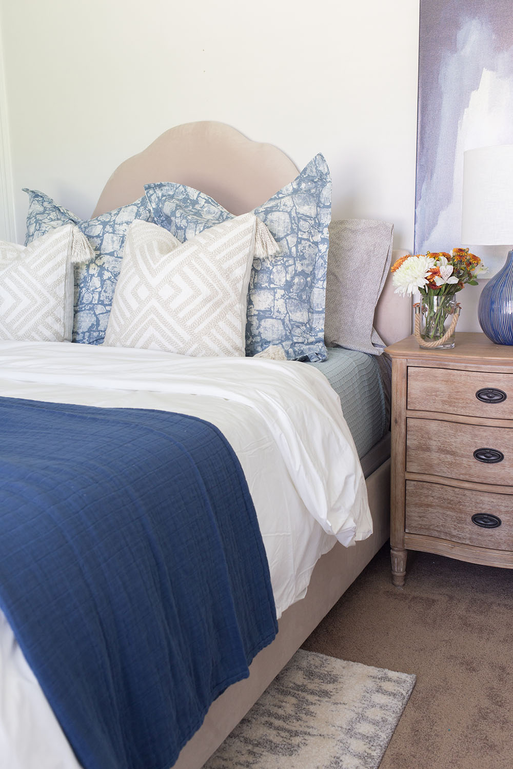 A guest bedroom decorated in light colors with blue accents.