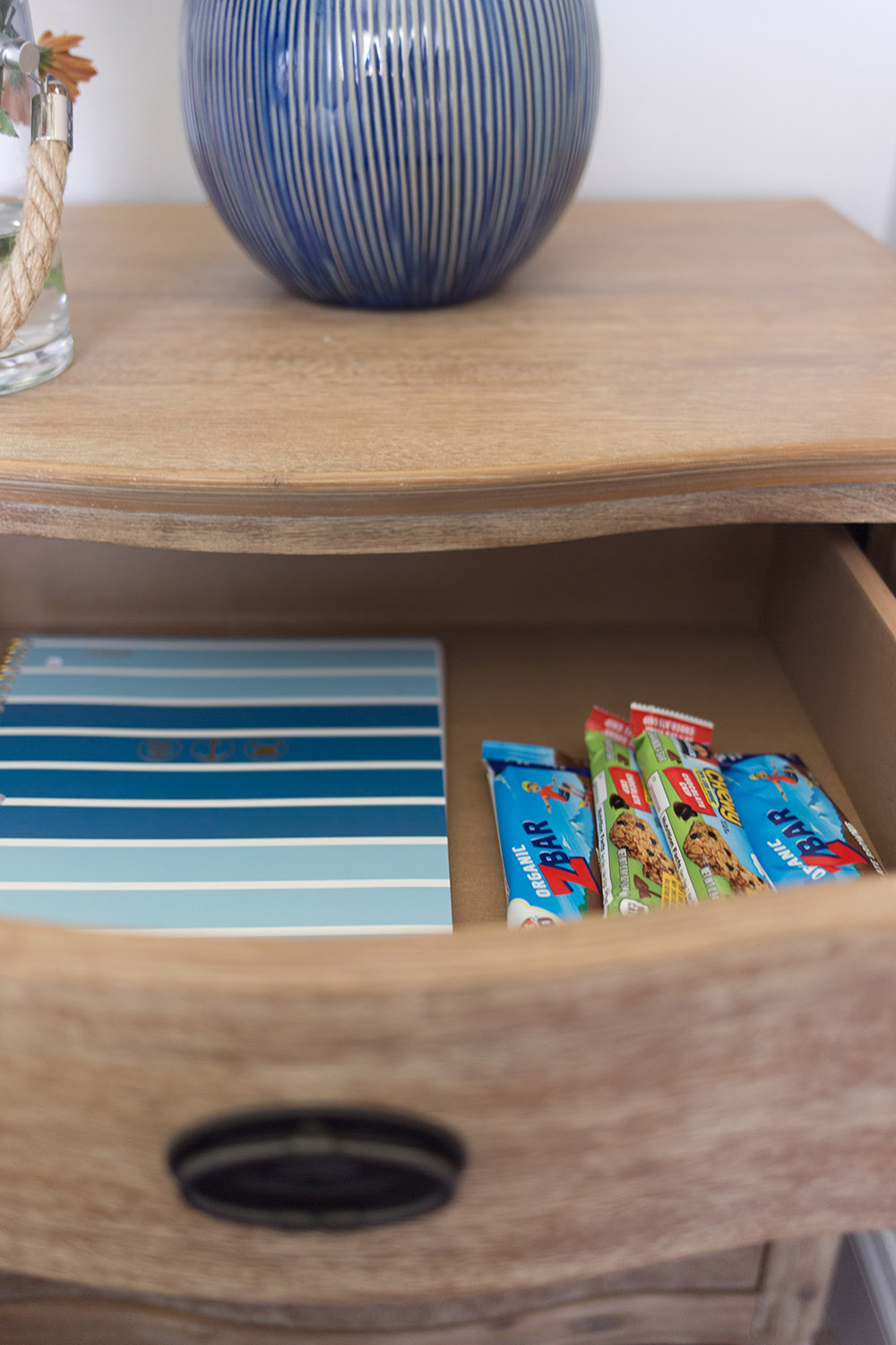 The inside of a nightstand draw filled with snacks.