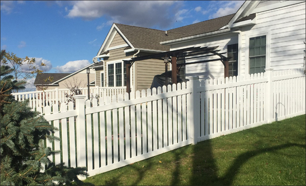 White picket fencing stands at the edge of a yard. 