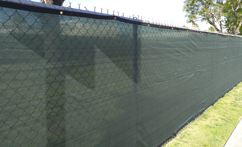 A green mesh privacy screen covers a chain link fence