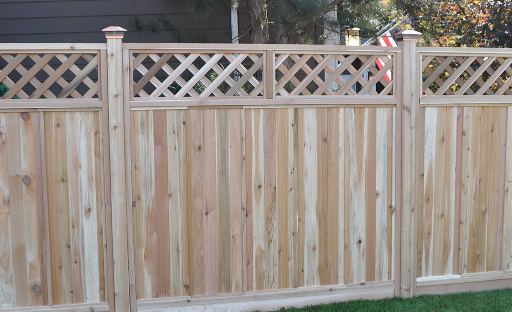 Lattice accents top a wooden fence that has decorative posts