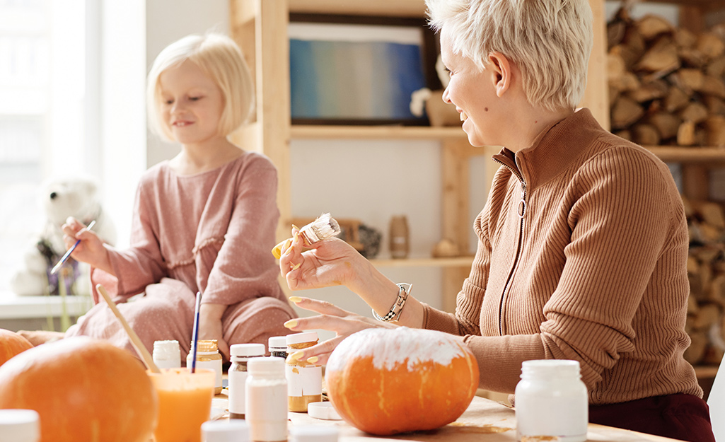 A woman and child painting pumpkins.