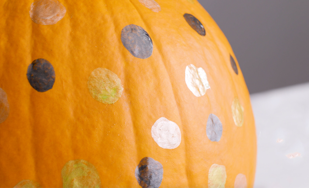 A pumpkin with black, silver, gold and white polka dots.